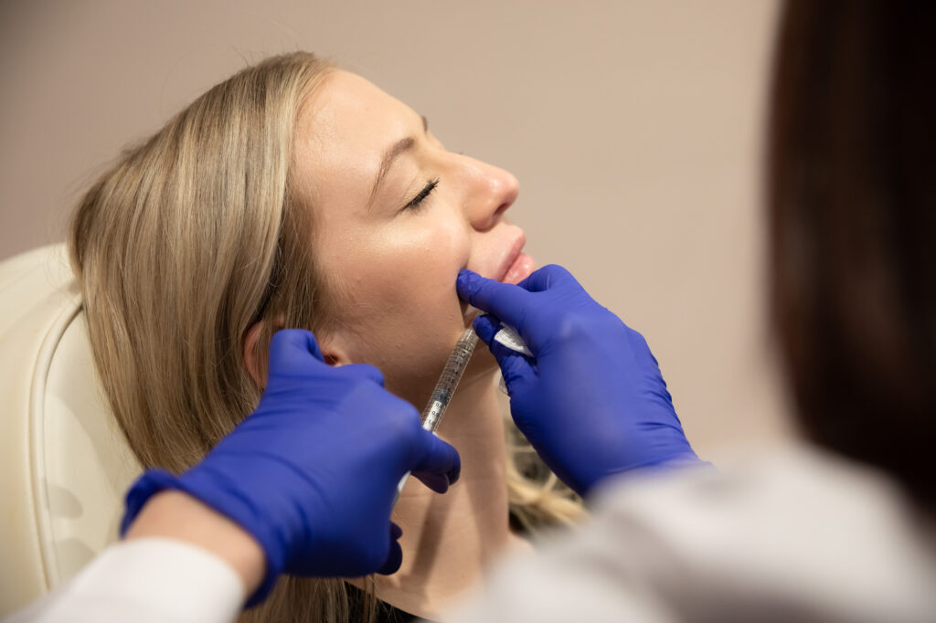 A provider at Harmonized carefully administers jawline filler in Tallahassee. Wearing surgical gloves, the provider injects the filler into the patient's jawline and chin to boost volume and refine the shape.