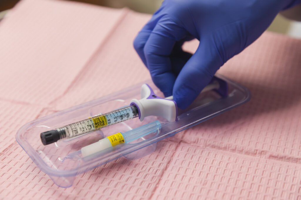 A close-up of fillers in Thomasville, GA, being prepared by a provider at Harmonized. Wearing surgical gloves, the provider carefully removes the filler syringe, which is pre-loaded with the desired units of filler for treatment.