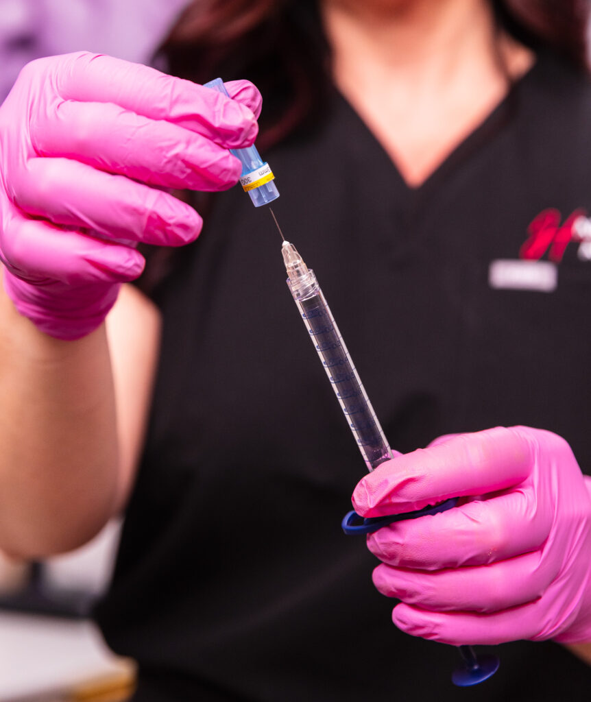 A provider at Harmonized Aesthetics prepares a syringe of dermal filler. Dermal fillers are often used for facial balancing near Cairo, GA, treatments. 